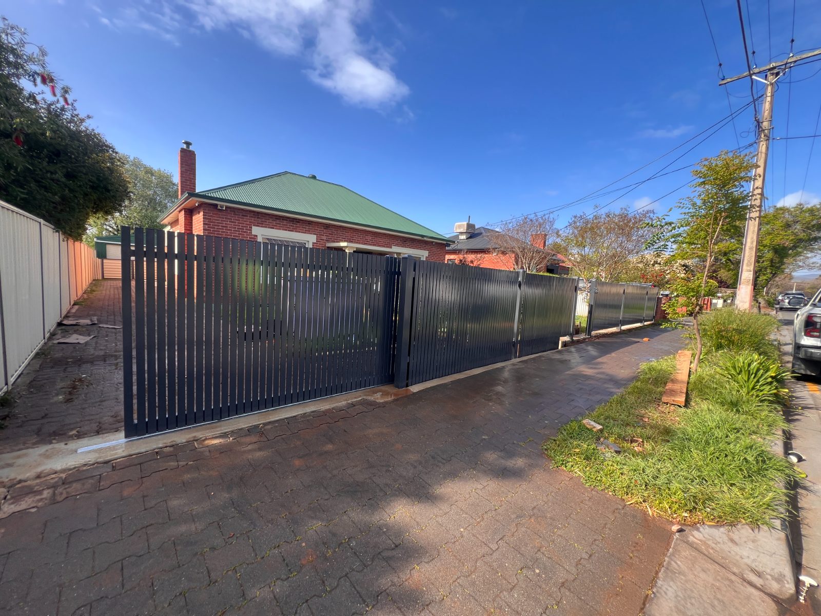 Steel driveway gate re-hung on brick pillars — real AOI job